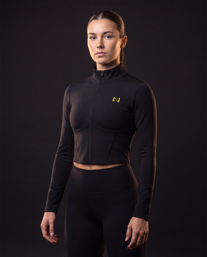Model wearing the NPRWLR Women's Full-Zip Sports Jacket in black, front view showing the stand collar, full-length zip and yellow N chest mark